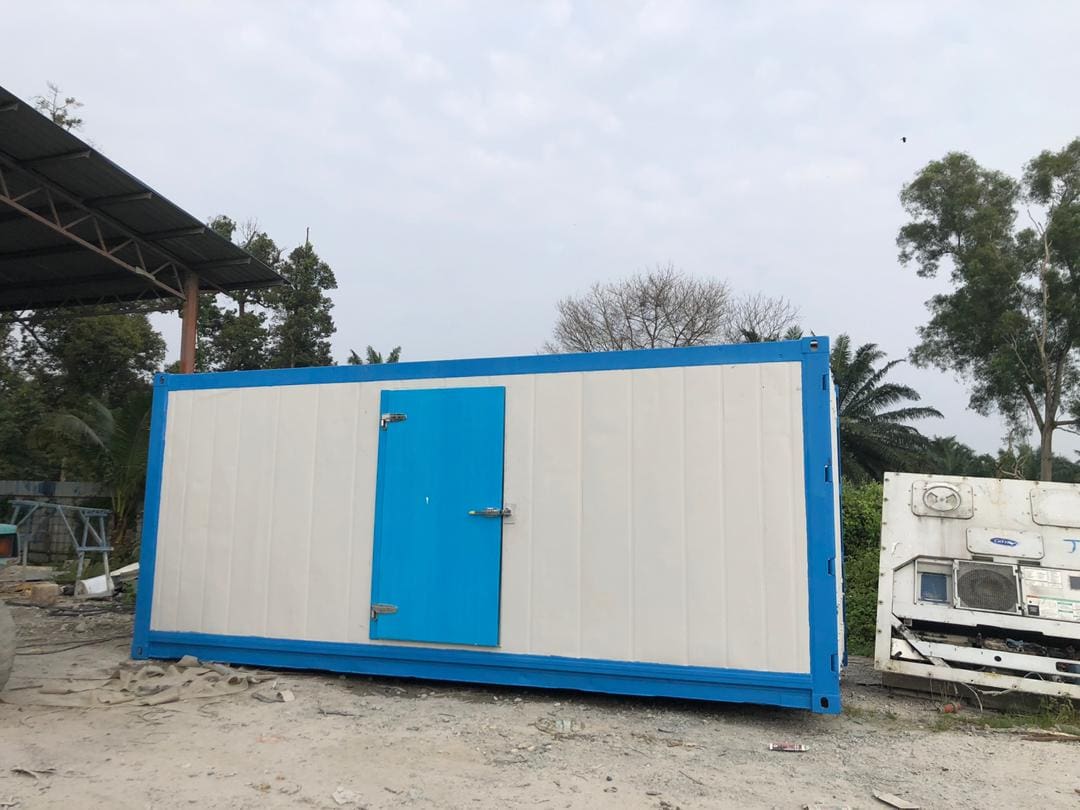 A blue and white portable reefer container with doors under an open-sided shelter.