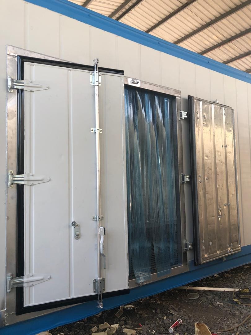 Industrial walk-in cold storage doors with heavy-duty latches and plastic strip curtains.