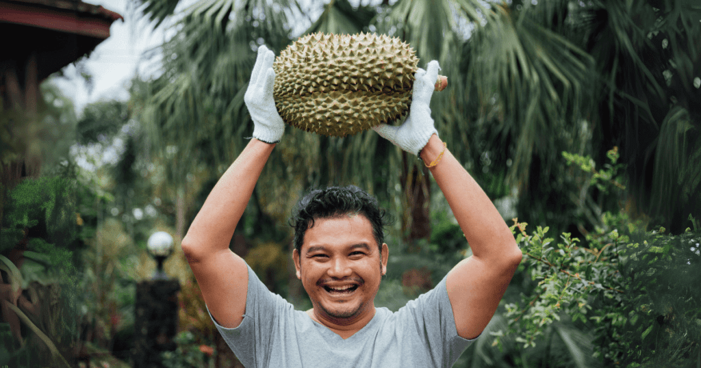 a guy holding durian up with happy smile