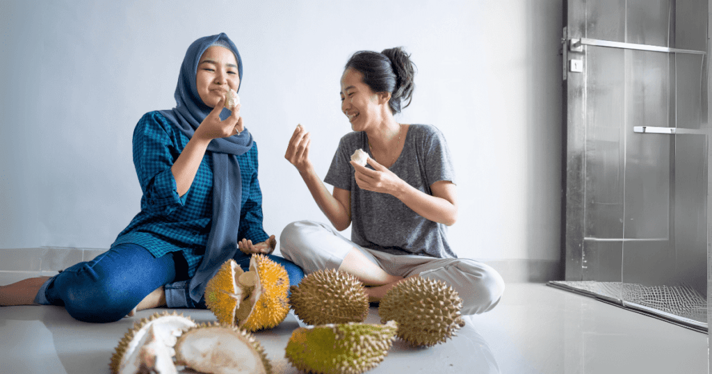 one malay lady enjoy eating durian happily with her chinese friend